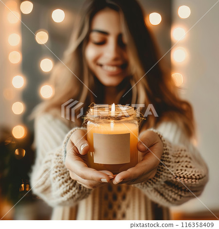 Happy smiling young woman holding candle jar in her hands, front view candle jar mockup, handmade candles lit Happy smiling young woman holding candle jar in her hands, front view candle jar mockup, handmade candles lit 116358409
