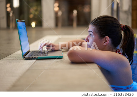 Woman Using Laptop at Pool Edge 116358426