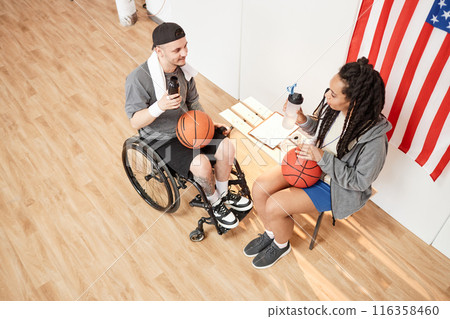 High angle view at basketball player with disability using wheelchair talking break and talking to friend during practice indoors 116358460