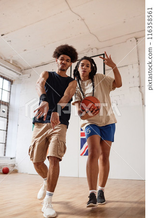 Vertical full length shot of two Black teenagers boy and girl playing basketball together and walking towards camera recording video for social media 116358561