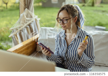 A beautiful girl smokes an electrode cigarette and uses a smartphone. Event Organizer A beautiful girl smokes an electrode cigarette and uses a smartphone. Event Organizer 116358575