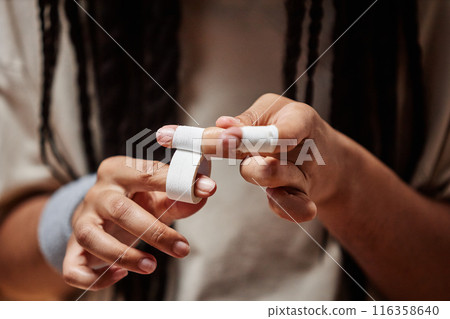 Close up of unrecognizable basketball player wrapping fingers with tape preparing for match copy space 116358640