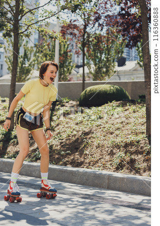 Shouting of joy, young girl on retro roller skaters listening music on vintage player and training on sunny day at park. 116360888