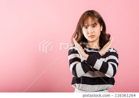 Portrait Asian beautiful young woman unhappy or confident standing wear holding two cross arms say no X sign, studio shot isolated pink background, Thai female pose reject gesture with copy space 116361264