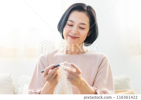 Senior woman knitting in the living room Senior woman knitting in the living room 116361422