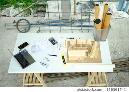 Top view Architectural house model, laptop and blueprints on table at construction site Top view Architectural house model, laptop and blueprints on table at construction site 116361741