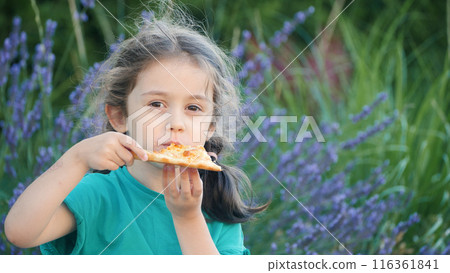 Portrait of a cute girl happily eating pizza in the backyard. 116361841