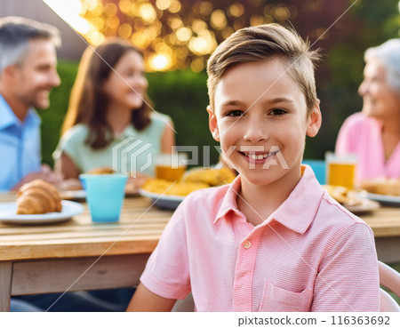 Happy Young Boy Celebrating Birthday with Family and Friends in a Backyard Party 116363692