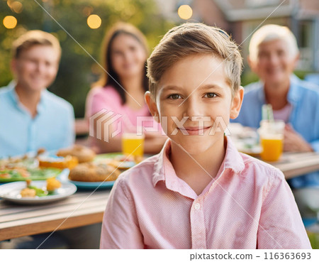 Happy Young Boy Celebrating Birthday with Family and Friends in a Backyard Party 116363693