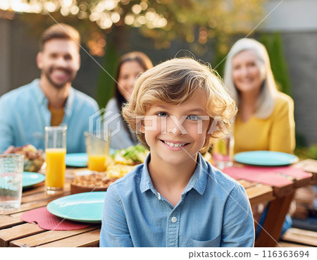 Happy Young Boy Celebrating Birthday with Family and Friends in a Backyard Party 116363694