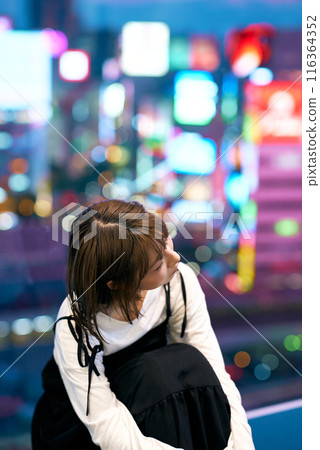 A young woman and a shining downtown at night 116364352