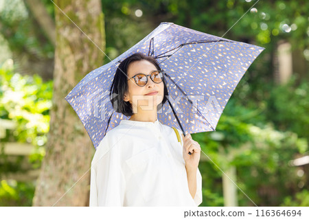撐著陽傘在公園散步的中年婦女 撐著陽傘在公園散步的中年婦女 116364694