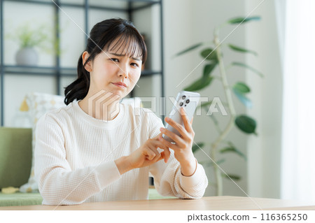 年輕女子在客廳看智慧型手機 116365250