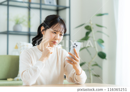 年輕女子在客廳看智慧型手機 116365251