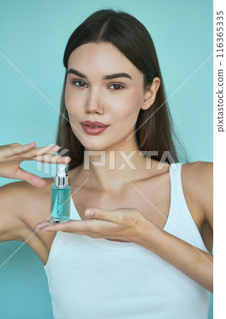Skincare Beauty. Woman Holding Skincare Serum Bottle Against Light Blue Background Skincare Beauty. Woman Holding Skincare Serum Bottle Against Light Blue Background 116365335