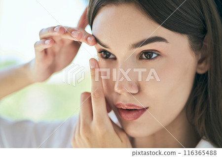 Woman Inserting Contact Lens with Care and Precision Woman Inserting Contact Lens with Care and Precision 116365488