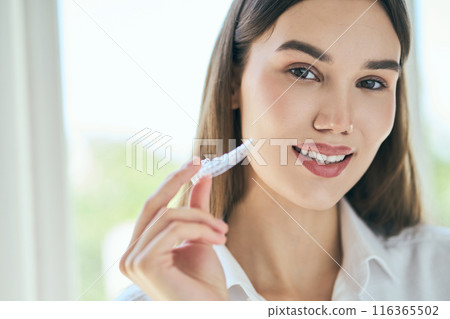 Woman Holding Clear Aligners for Teeth Straightening 116365502