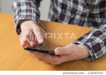 Close-up of a person's hand operating a smartphone Close-up of a person's hand operating a smartphone 116365591