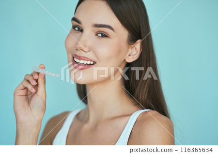 Dental Care. Woman Holding Dental Aligner Against Blue Background Dental Care. Woman Holding Dental Aligner Against Blue Background 116365634