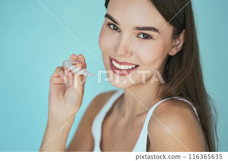 Woman Holding Dental Aligners On Blue Background 116365635