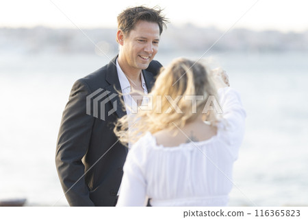 A man and a woman are standing on a beach, smiling at each other A man and a woman are standing on a beach, smiling at each other 116365823