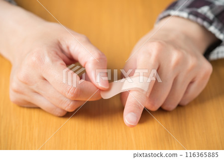 The hand of a person putting a bandage on a finger 116365885