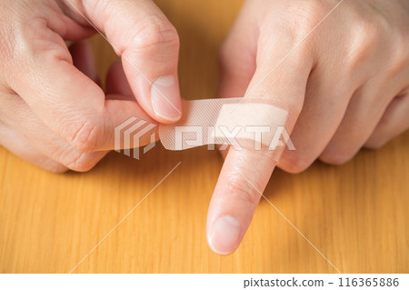 The hand of a person putting a bandage on a finger 116365886