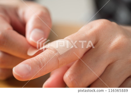 The hand of a person putting a bandage on a finger 116365889