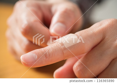 The hand of a person putting a bandage on a finger 116365890