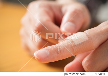 The hand of a person putting a bandage on a finger 116365891