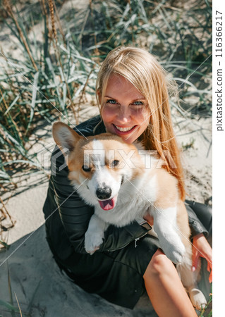 Happy Woman Holding a Smiling Corgi on a Sunny Day Happy Woman Holding a Smiling Corgi on a Sunny Day 116366217
