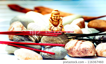 Statuette of a Buddhist monk among incense and various stones Statuette of a Buddhist monk among incense and various stones 116367460