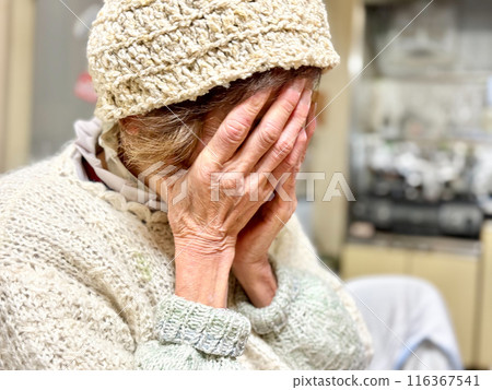 Elderly woman covering her face with both hands Elderly woman covering her face with both hands 116367541