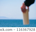 Person holding a water bottle in the sea 116367928