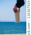 Person holding a water bottle in the sea 116367929