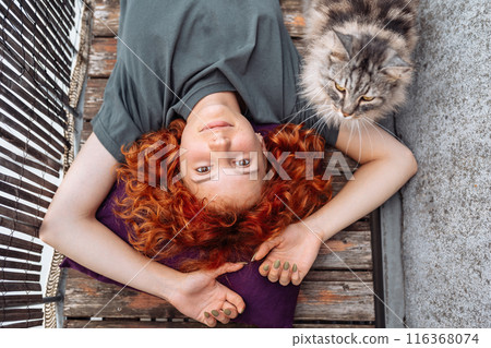portrait red-haired curly young woman enjoying relaxation on balcony or terrace portrait red-haired curly young woman enjoying relaxation on balcony or terrace 116368074