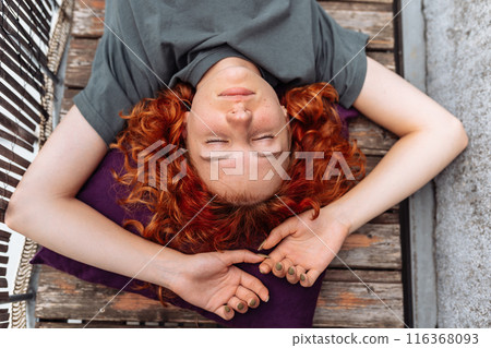 portrait red-haired curly young woman enjoying relaxation on balcony or terrace portrait red-haired curly young woman enjoying relaxation on balcony or terrace 116368093