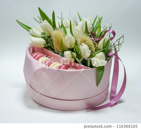 Pink box with tulip flowers and sweet macarons on a white background Pink box with tulip flowers and sweet macarons on a white background 116368185
