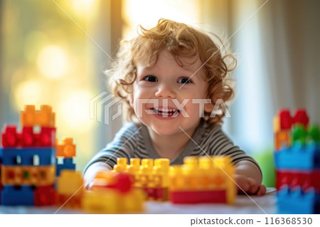 Happy curly toddler boy playing with colorful children's construction set on a sunny day. Children's games and childhood 116368530