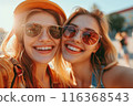 Two happy caucasian girls take a selfie outdoors on a sunny day. Smiling girlfriends take pictures on a mobile phone. Lifestyle. Close-up 116368543