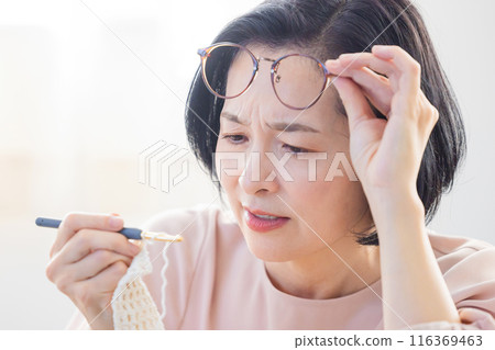 A middle-aged woman who is having difficulty seeing what is in front of her 116369463
