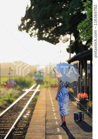 一個帶著陽傘和直線火車線的女人在夏日的夕陽下閃閃發光 116369702