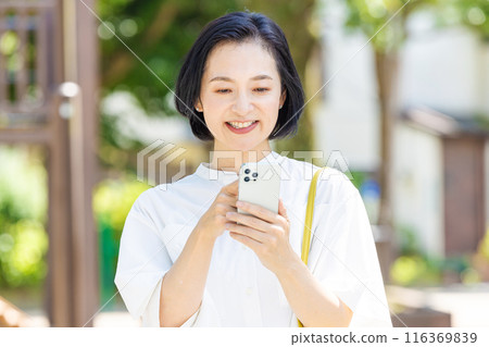 中年婦女在新鮮的綠色植物中看著智慧型手機 116369839