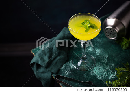 Tropical yellow lemon cocktail on green background Tropical yellow lemon cocktail on green background 116370203