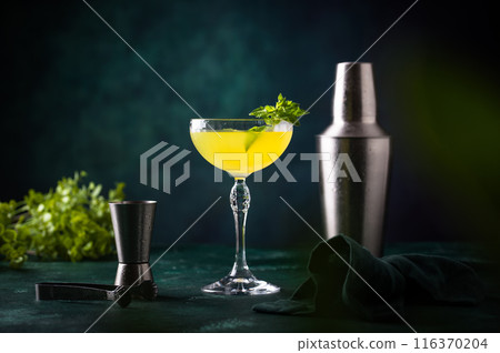 Tropical yellow lemon cocktail on green background Tropical yellow lemon cocktail on green background 116370204