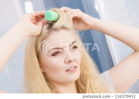 Blonde woman using hair rollers Blonde woman using hair rollers 116370452