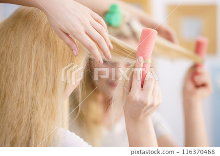Blonde woman using hair rollers Blonde woman using hair rollers 116370468