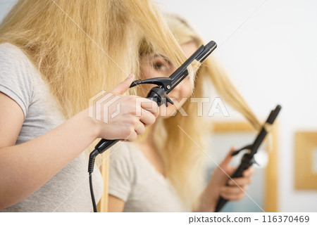 Woman using hair curler Woman using hair curler 116370469