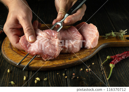 Chef preparing meat steaks on the kitchen table before going on a picnic. Concept of cooking juicy lamb barbecue. Asian cuisine Chef preparing meat steaks on the kitchen table before going on a picnic. Concept of cooking juicy lamb barbecue. Asian cuisine 116370712