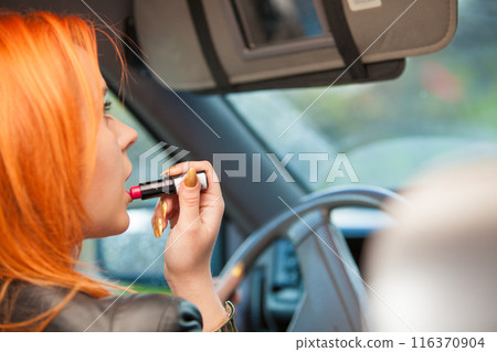 girl painting her lips doing make up while driving the car. 116370904